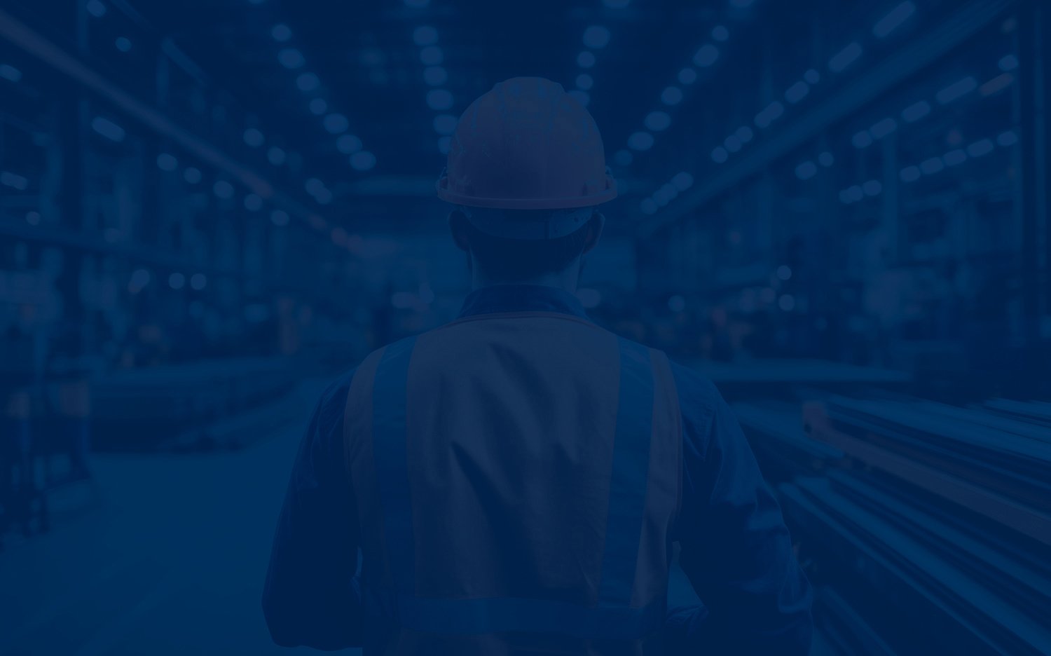 Back view of a factory worker in a hard hat and safety vest inspecting equipment in a brightly lit industrial facility with blue overlay