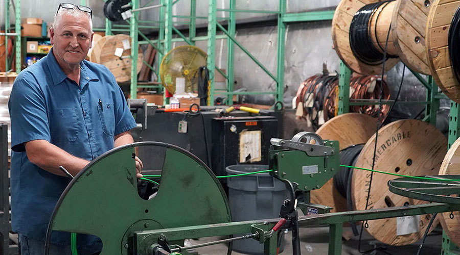 man standing behind a wire reel getting ready to pull wire
