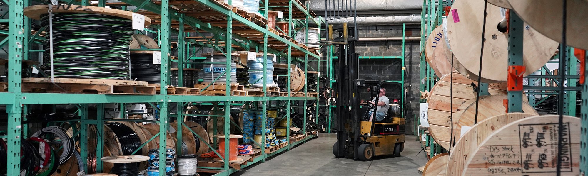 warehouse full of material and a guy on a forklift driving in the warehouse
