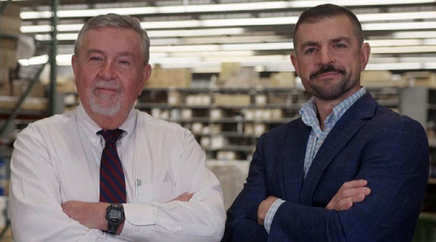two men standing in a warehouse with their arms crossed