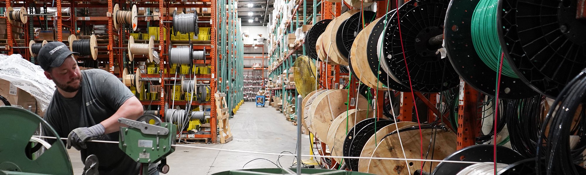 man pulling electrical wire in a warehouse